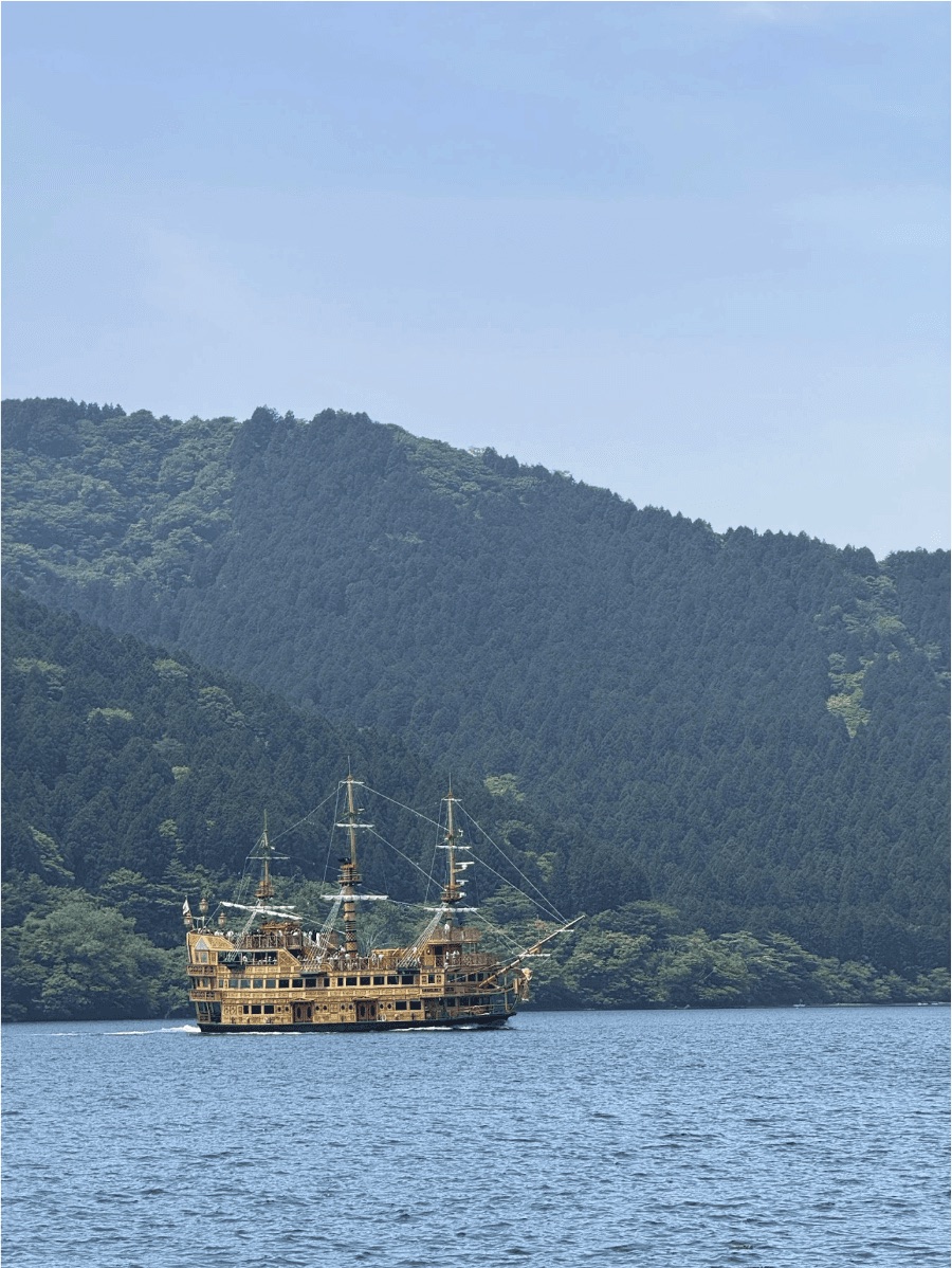 A wooden pirate-style boat on a lake surrounded by mountains