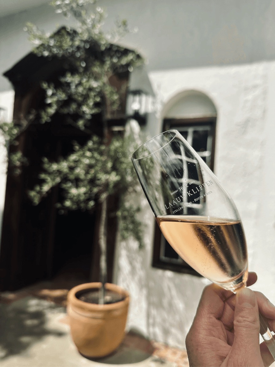 A glass of champagne held up outside a white building