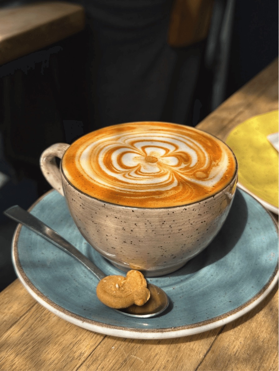 Latte art in a cup on a saucer with a biscuit
