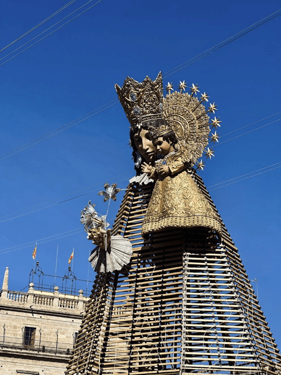 An ornate golden religious statue against a blue sky